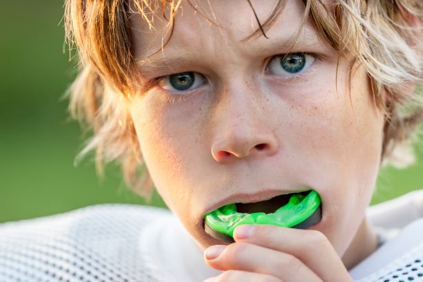 A young boy wearing a sports mouthguard.